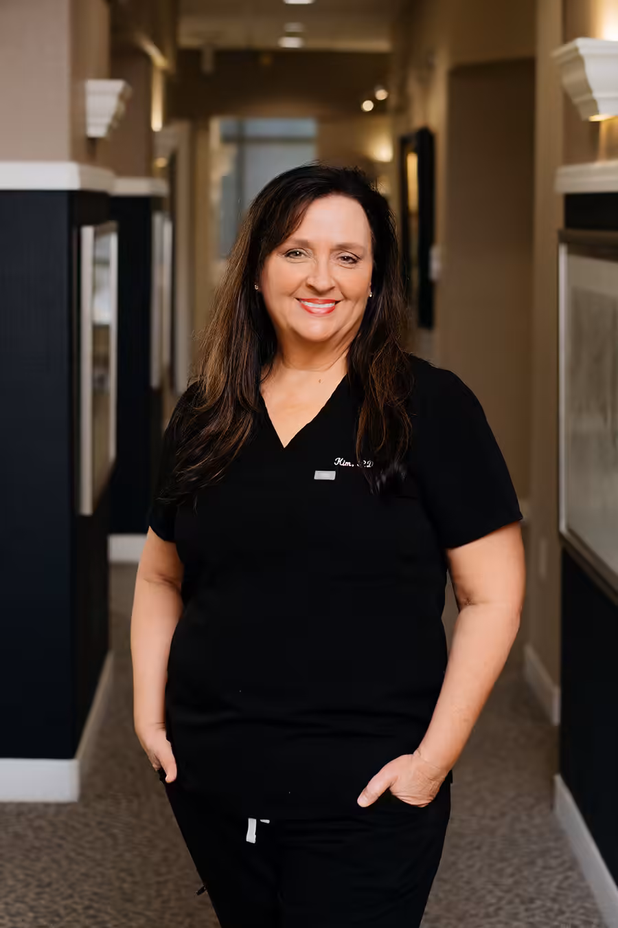 Kim Portrait of Kim, dental hygienist at Rainwater Drake Dental, smiling in the office hallway.